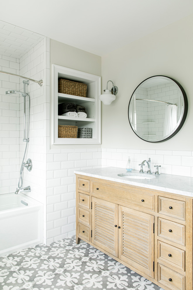 This is an example of a beach style bathroom in New York with beaded inset cabinets, light wood cabinets, an alcove tub, an open shower, beige tile, subway tile, grey walls, an undermount sink, a hinged shower door and grey benchtops.
