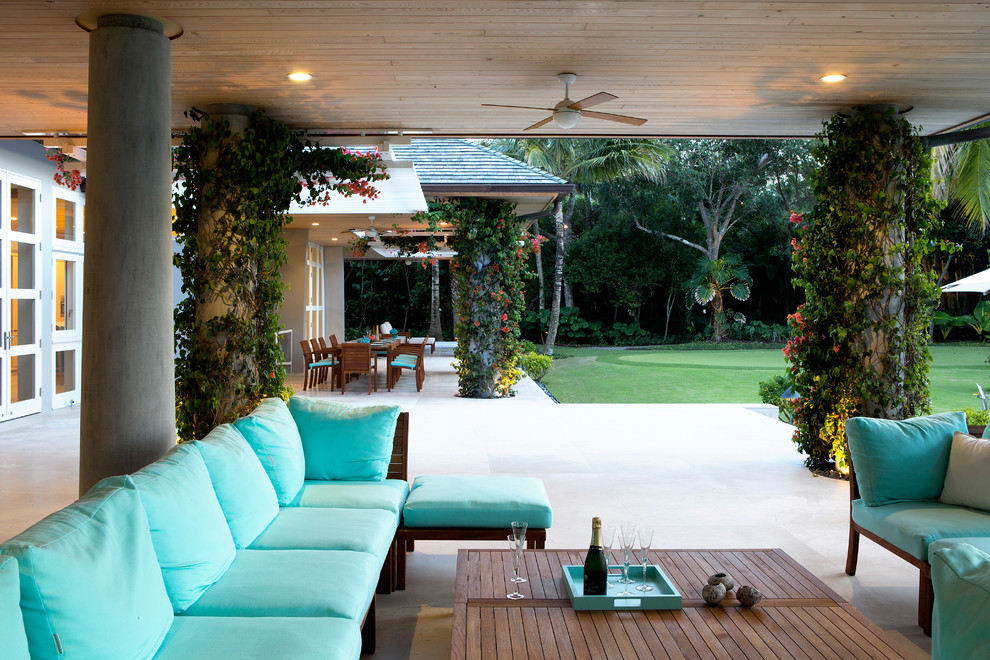 This is an example of a large tropical backyard patio in Miami with a roof extension.