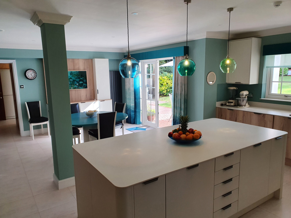 Photo of a contemporary u-shaped kitchen in Dorset with flat-panel cabinets, light wood cabinets, solid surface benchtops, white splashback, engineered quartz splashback, laminate floors, with island, beige floor and white benchtop.