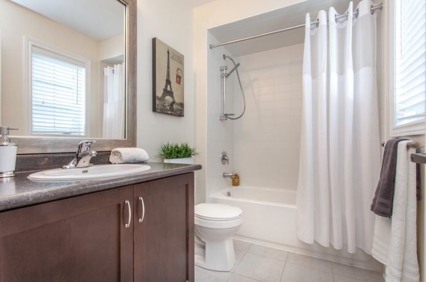 Inspiration for a mid-sized contemporary 3/4 bathroom in Toronto with a drop-in sink, an alcove tub, a shower/bathtub combo, a two-piece toilet, porcelain tile, beige walls, ceramic floors, shaker cabinets, dark wood cabinets, laminate benchtops and beige tile.