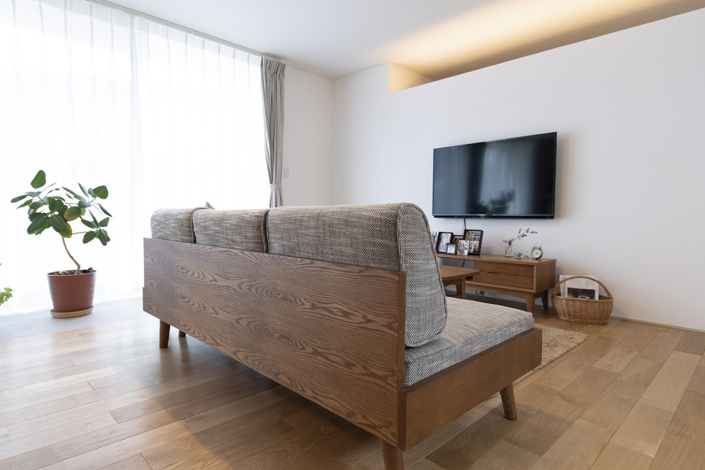 Offenes Nordisches Wohnzimmer mit weißer Wandfarbe, braunem Holzboden, TV-Wand, Tapetendecke und Holzdielenwänden in Sonstige