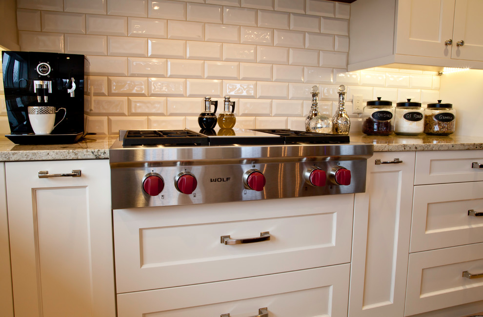 Large transitional l-shaped light wood floor and brown floor open concept kitchen photo with an undermount sink, shaker cabinets, white cabinets, granite countertops, white backsplash, subway tile backsplash, paneled appliances and an island