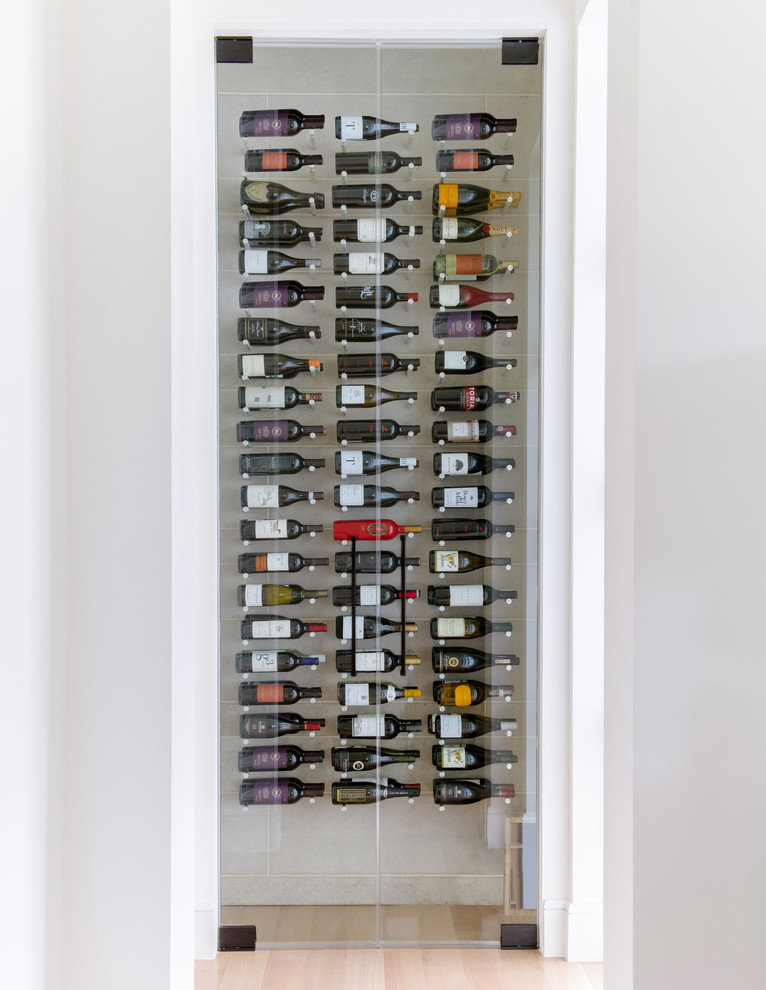 Small mediterranean wine cellar in Dallas with light hardwood floors and display racks.