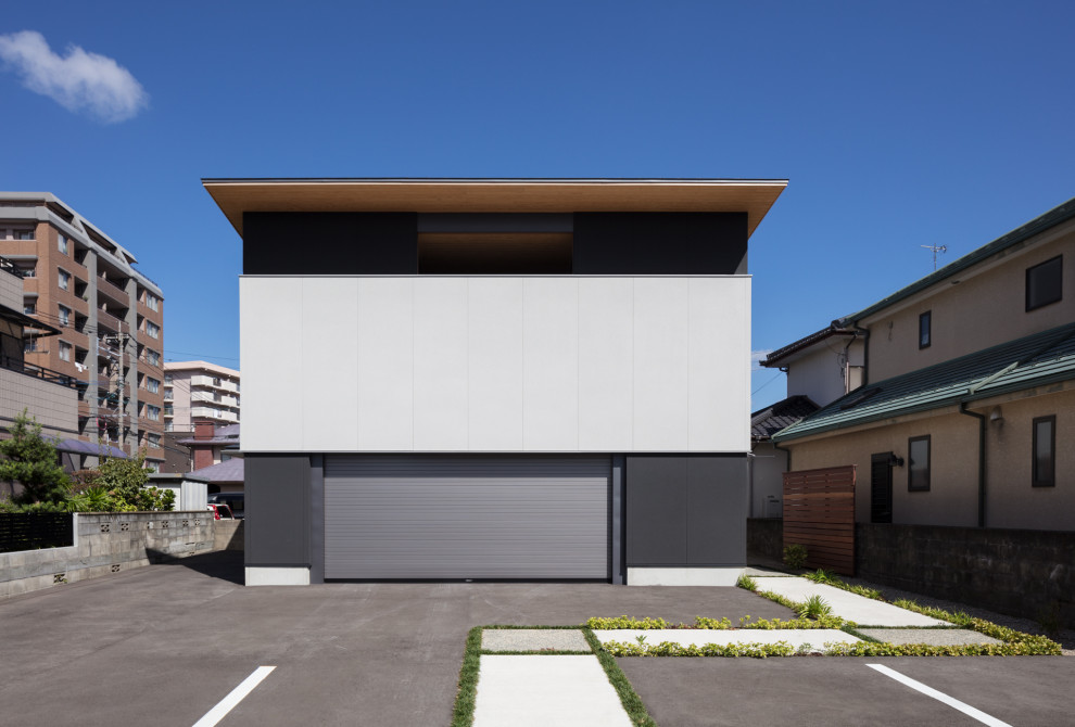 Small modern two-storey grey house exterior in Fukuoka with mixed siding, a shed roof and a metal roof.