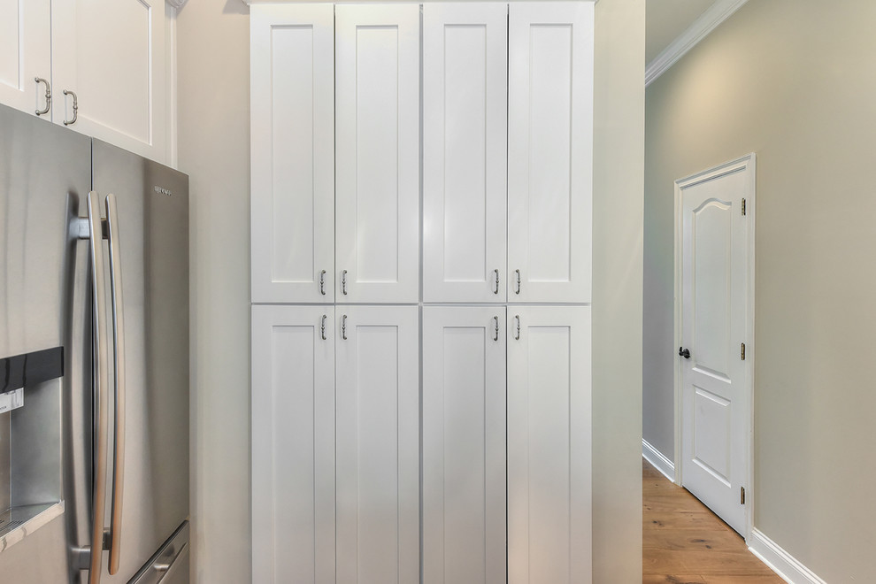 Inspiration for a large transitional l-shaped medium tone wood floor home design remodel in Jacksonville with a farmhouse sink, shaker cabinets, quartz countertops and an island