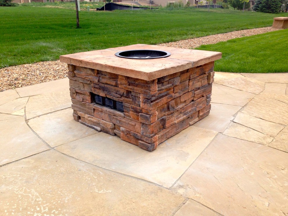 Photo of a mid-sized country backyard patio in Denver with a fire feature, natural stone pavers and no cover.
