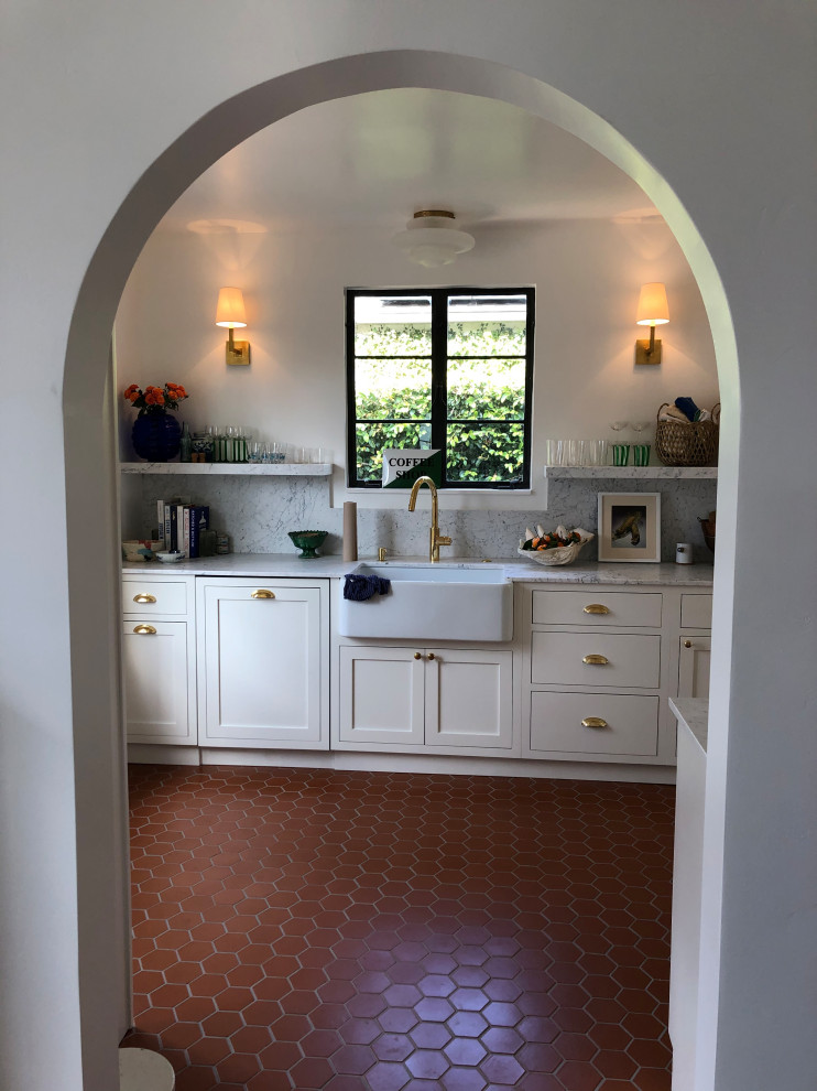 Enclosed kitchen - small mediterranean galley terra-cotta tile and red floor enclosed kitchen idea in Santa Barbara with a farmhouse sink, shaker cabinets, white cabinets, marble countertops, white backsplash, marble backsplash, stainless steel appliances, no island and white countertops