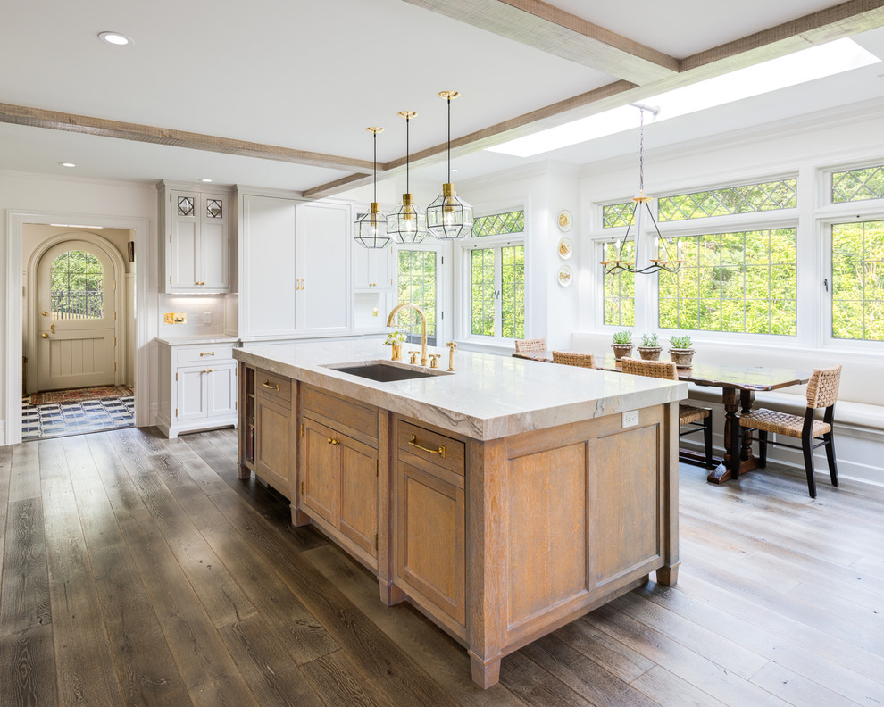 This is an example of a country eat-in kitchen in New York with an undermount sink, shaker cabinets, medium wood cabinets, white splashback, dark hardwood floors and with island.