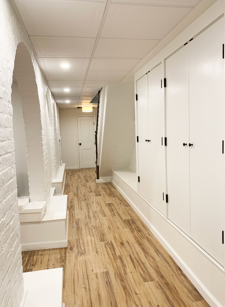 Inspiration pour un sous-sol traditionnel de taille moyenne avec un mur blanc, un sol en vinyl et un sol marron.