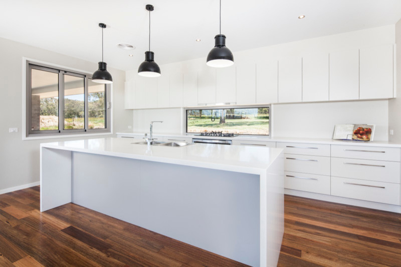 This is an example of a modern eat-in kitchen in Melbourne with a double-bowl sink, white cabinets, soapstone benchtops, white splashback and stainless steel appliances.