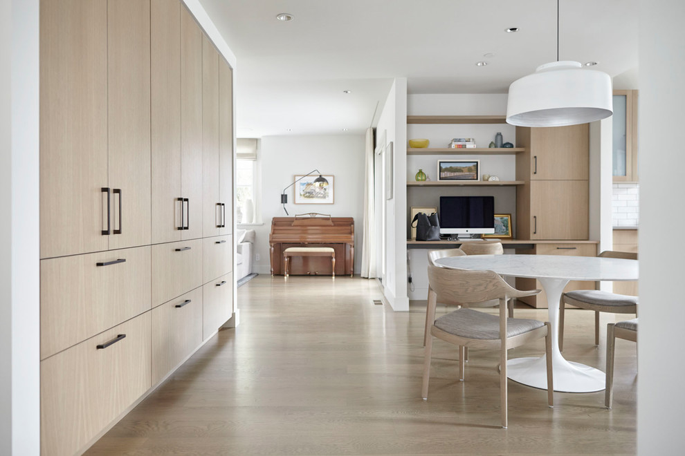 Design ideas for a large modern u-shaped eat-in kitchen in San Francisco with an undermount sink, flat-panel cabinets, light wood cabinets, wood benchtops, stone tile splashback, panelled appliances, light hardwood floors, with island and white benchtop.