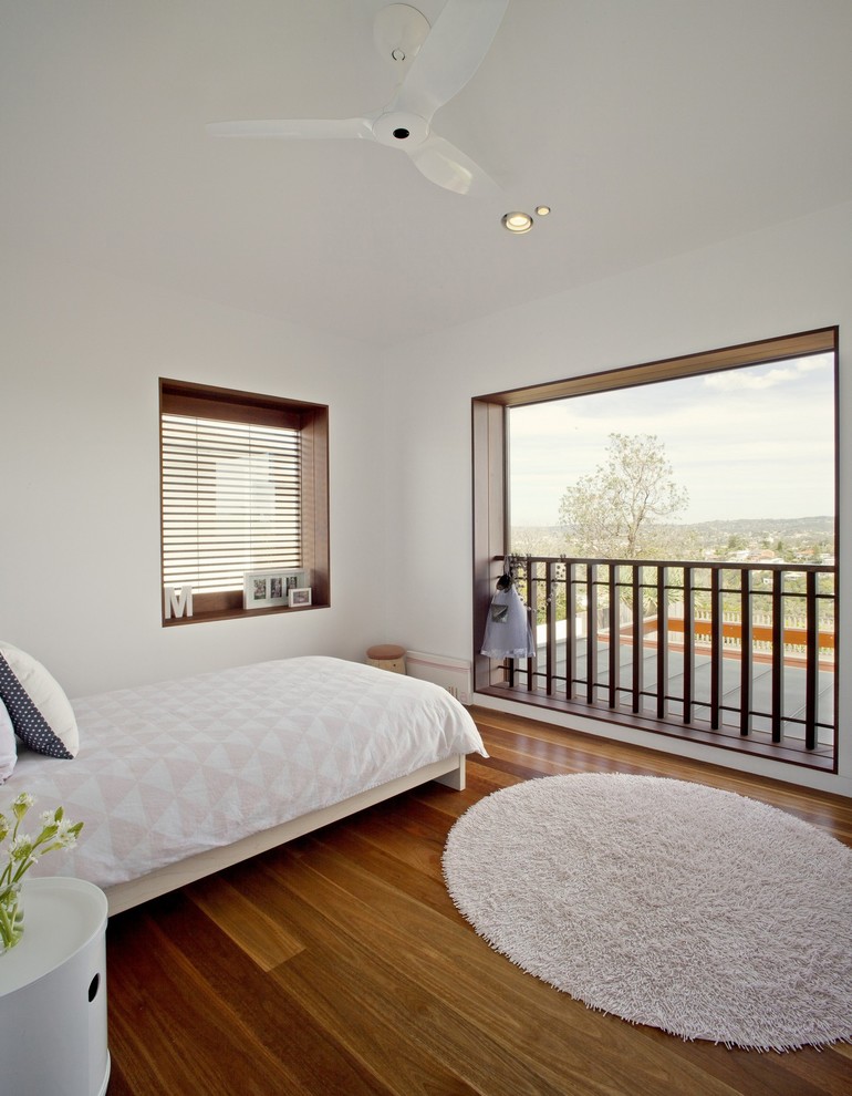 Photo of a mid-sized contemporary bedroom in Sydney with white walls and medium hardwood floors.