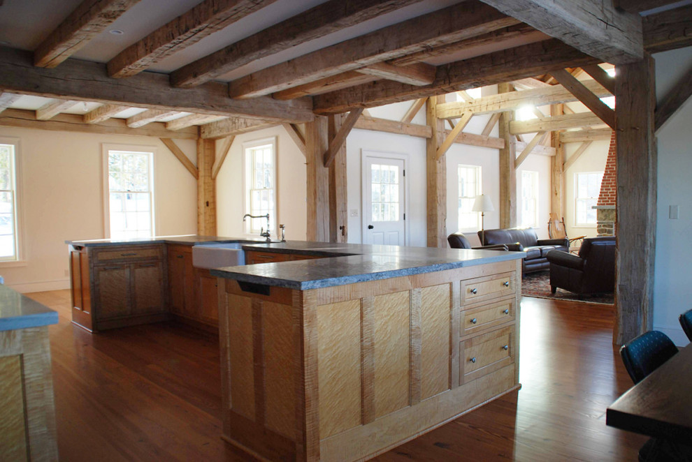 Example of a large medium tone wood floor open concept kitchen design with a farmhouse sink, light wood cabinets, soapstone countertops, gray backsplash, stone slab backsplash, stainless steel appliances, an island and gray countertops
