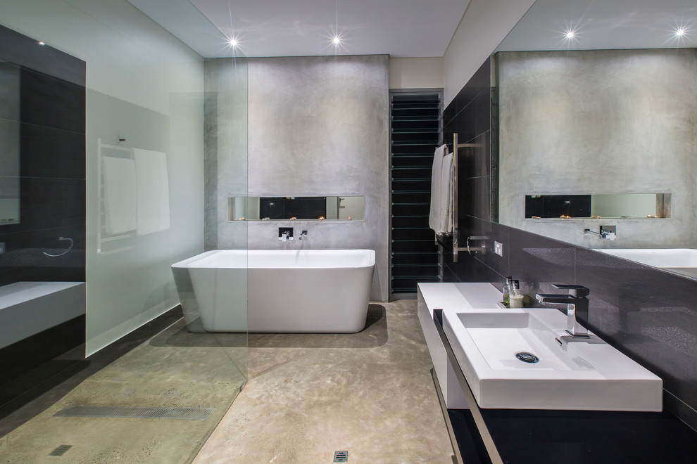 Modern bathroom in Perth with a freestanding tub, grey walls and concrete floors.