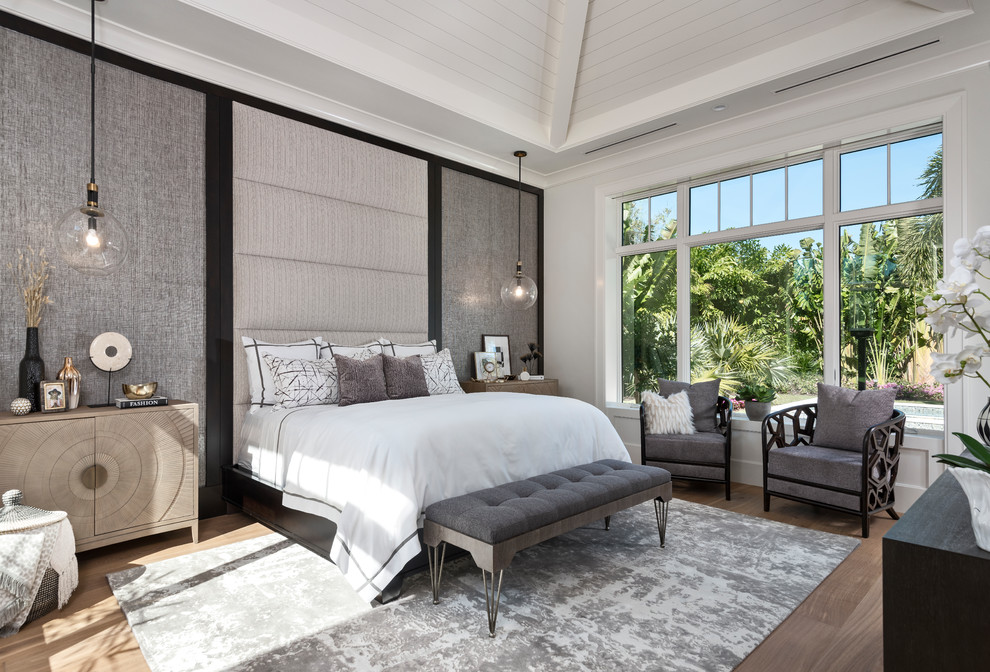 Design ideas for a tropical guest bedroom in Miami with white walls, medium hardwood floors and brown floor.