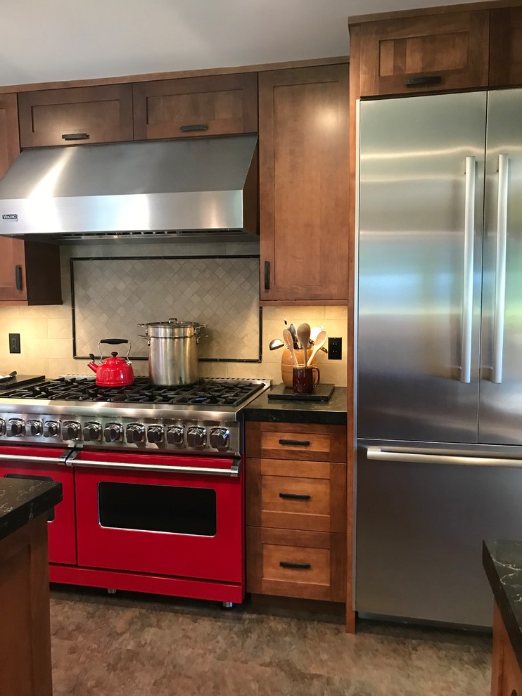 Photo of a mid-sized arts and crafts u-shaped eat-in kitchen in San Francisco with a single-bowl sink, shaker cabinets, medium wood cabinets, quartz benchtops, beige splashback, stone tile splashback, stainless steel appliances, cork floors, with island, multi-coloured floor and black benchtop.