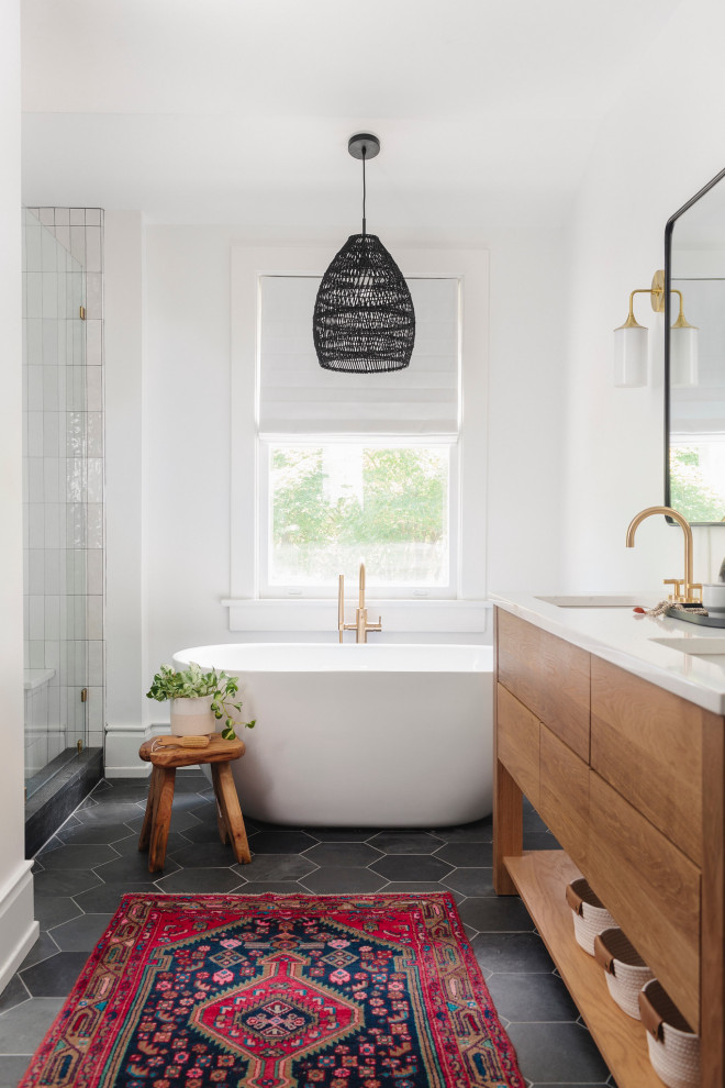 Exempel på ett mellanstort modernt vit vitt en-suite badrum, med skåp i ljust trä, ett fristående badkar, vit kakel, stenkakel, vita väggar, klinkergolv i keramik, ett undermonterad handfat, bänkskiva i akrylsten, svart golv och dusch med gångjärnsdörr