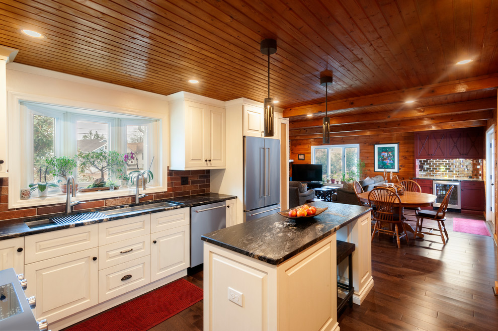 Example of a large transitional l-shaped dark wood floor and brown floor eat-in kitchen design in Philadelphia with an undermount sink, raised-panel cabinets, white cabinets, granite countertops, red backsplash, brick backsplash, stainless steel appliances, an island and black countertops