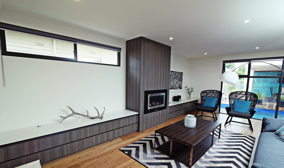 Mid-sized contemporary open concept living room in Melbourne with white walls, medium hardwood floors, a hanging fireplace and a wood fireplace surround.