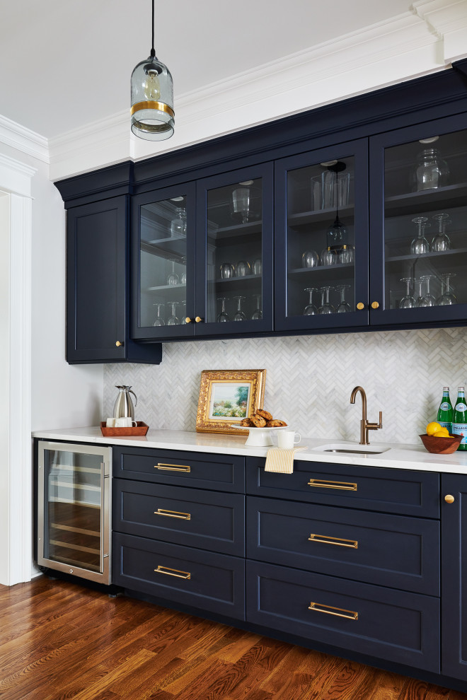 Inspiration for a transitional single-wall wet bar in New York with an undermount sink, shaker cabinets, blue cabinets, grey splashback, medium hardwood floors, brown floor and white benchtop.