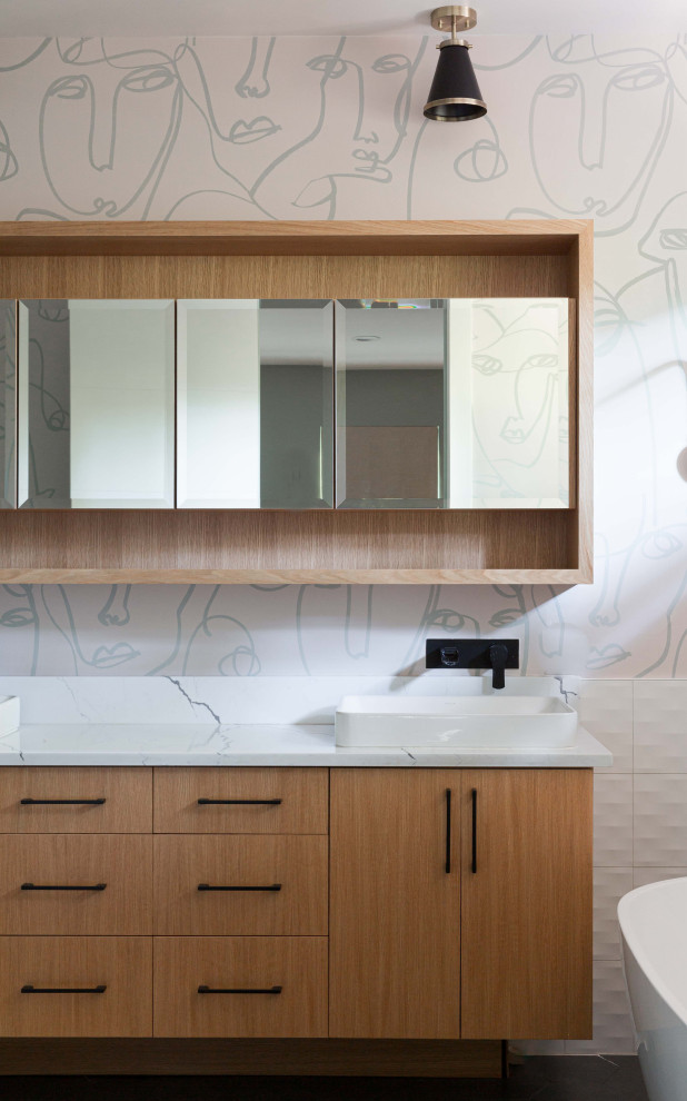 This is an example of a small contemporary master bathroom in Portland with flat-panel cabinets, light wood cabinets, a freestanding tub, white tile, porcelain tile, multi-coloured walls, ceramic floors, engineered quartz benchtops, black floor, white benchtops, a double vanity, a floating vanity and wallpaper.