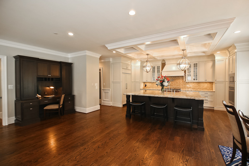 Open concept kitchen - large transitional u-shaped dark wood floor and brown floor open concept kitchen idea with a farmhouse sink, beaded inset cabinets, white cabinets, granite countertops, beige backsplash, ceramic backsplash, paneled appliances, an island and multicolored countertops