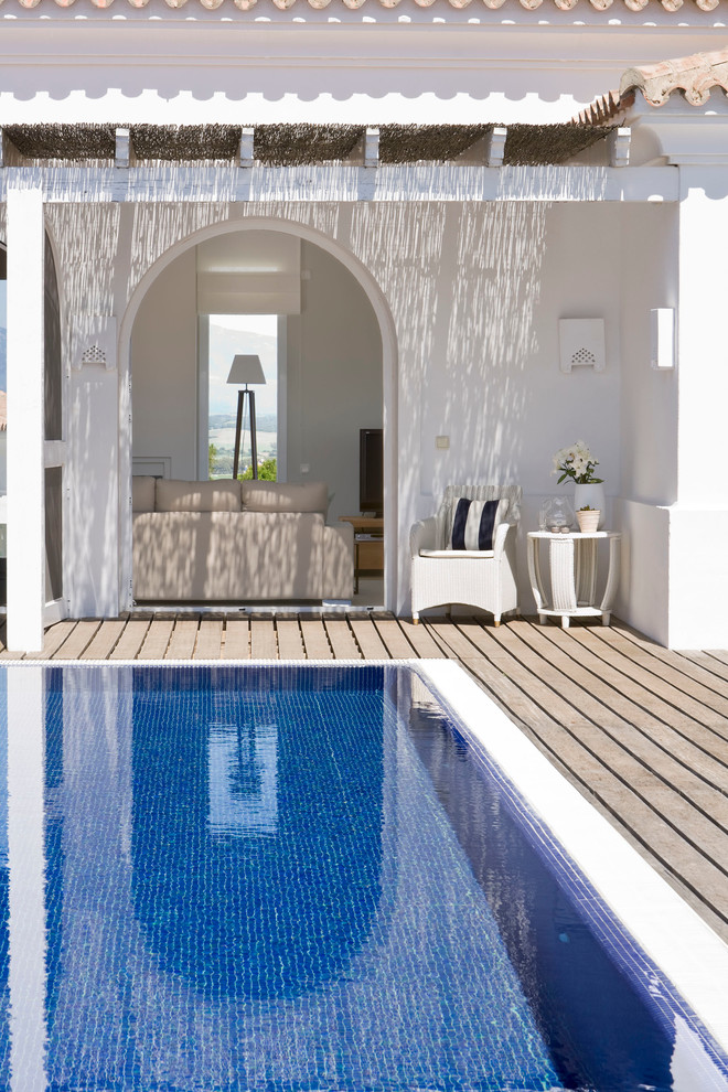 Inspiration for a mid-sized mediterranean rectangular lap pool in Malaga with a pool house and decking.