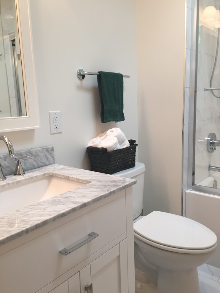 Mid-sized transitional gray tile and porcelain tile porcelain tile home design photo in Indianapolis with flat-panel cabinets, white cabinets, a one-piece toilet, white walls, an undermount sink and marble countertops