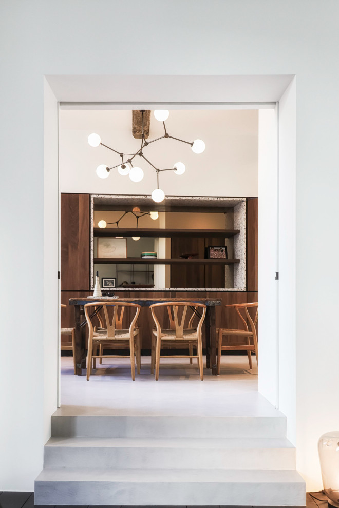 На фото: большая кухня-столовая в стиле модернизм с белыми стенами, бетонным полом, серым полом и балками на потолке с