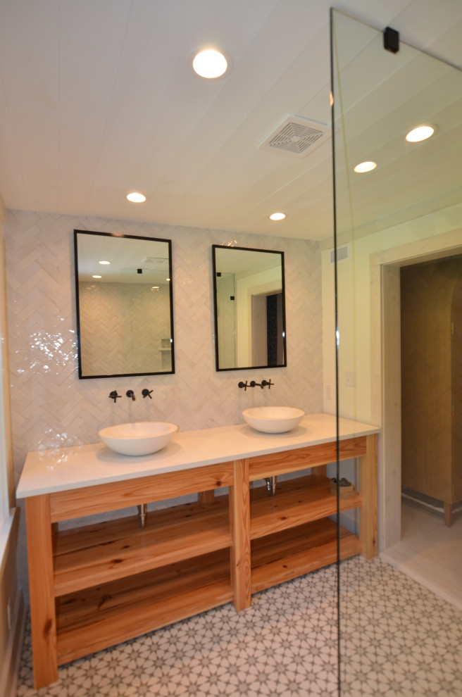 Inredning av ett lantligt stort vit vitt badrum med dusch, med öppna hyllor, skåp i mellenmörkt trä, en öppen dusch, en toalettstol med separat cisternkåpa, vit kakel, perrakottakakel, vita väggar, cementgolv, ett fristående handfat, bänkskiva i akrylsten, grått golv och med dusch som är öppen