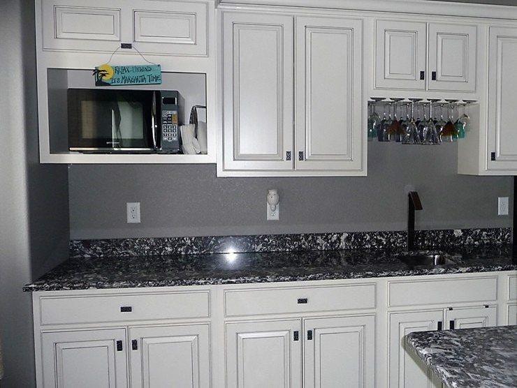 Photo of a mid-sized eclectic single-wall open plan kitchen in Other with an undermount sink, raised-panel cabinets, white cabinets, quartz benchtops and with island.