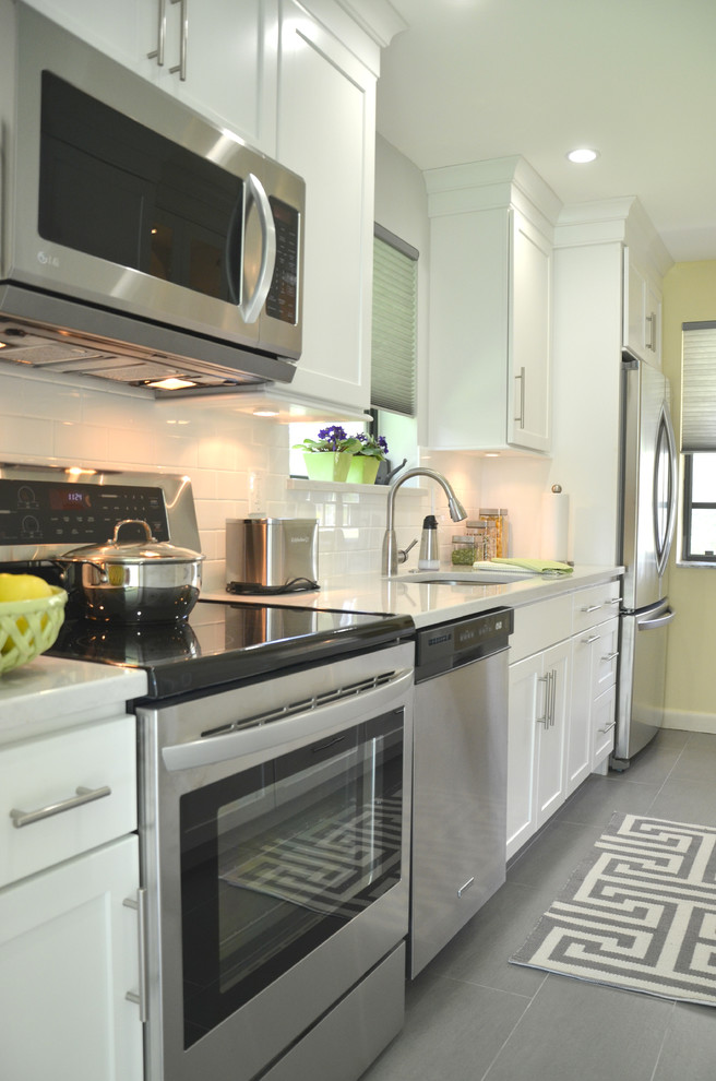 Inspiration for a small transitional galley separate kitchen in Miami with an undermount sink, flat-panel cabinets, white cabinets, quartz benchtops, white splashback, subway tile splashback, stainless steel appliances and porcelain floors.