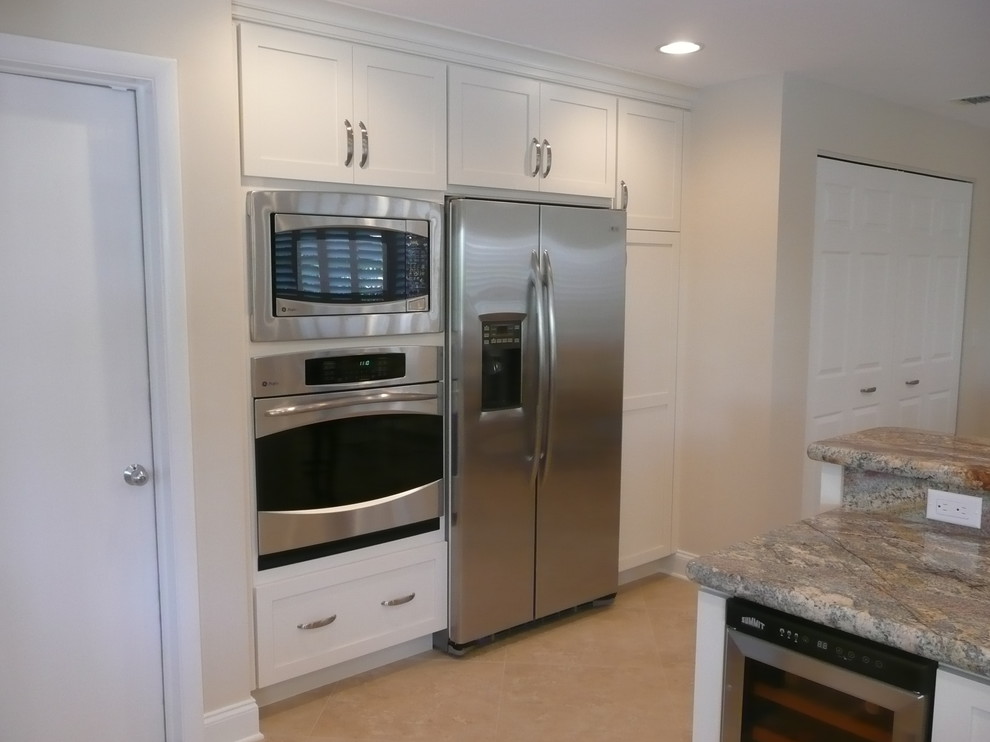 Kitchen pantry - mid-sized transitional u-shaped ceramic tile kitchen pantry idea in Miami with flat-panel cabinets, white cabinets, quartzite countertops, stainless steel appliances and a peninsula