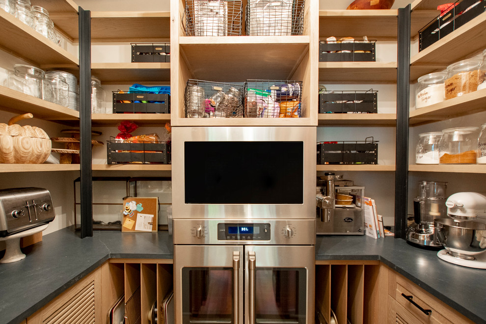 This is an example of a small country u-shaped kitchen pantry in Other with light wood cabinets, quartz benchtops, stainless steel appliances, light hardwood floors, brown floor, black benchtop and open cabinets.