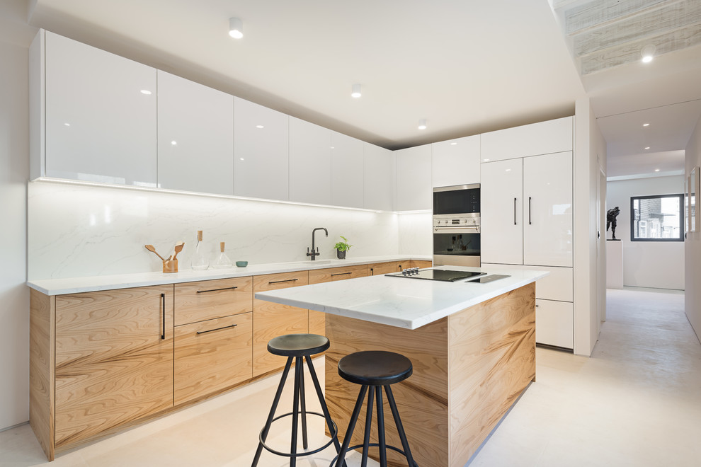 Design ideas for a contemporary l-shaped kitchen in Hampshire with a single-bowl sink, flat-panel cabinets, white cabinets, white splashback, stainless steel appliances, with island, white benchtop and beige floor.