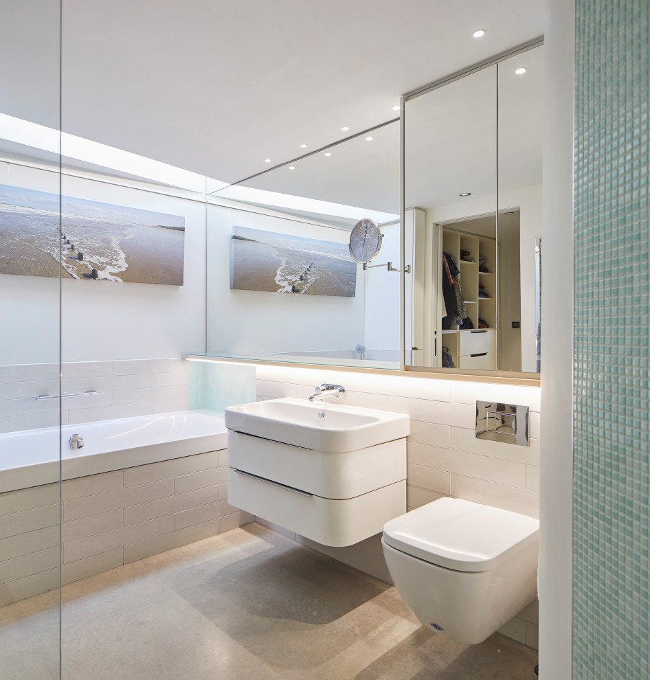 Example of a trendy white tile concrete floor, gray floor and single-sink alcove bathtub design in Cambridgeshire with flat-panel cabinets, white cabinets, a console sink and a floating vanity