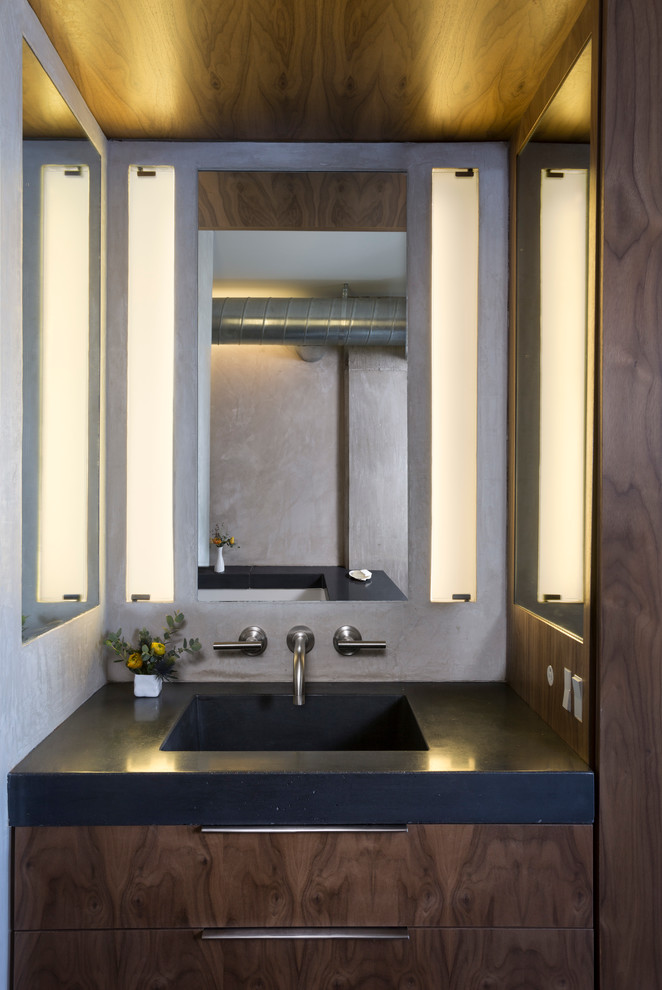 Photo of a small modern master bathroom in Austin with an integrated sink, flat-panel cabinets, dark wood cabinets, concrete benchtops, an undermount tub, an open shower, a wall-mount toilet, gray tile and grey walls.