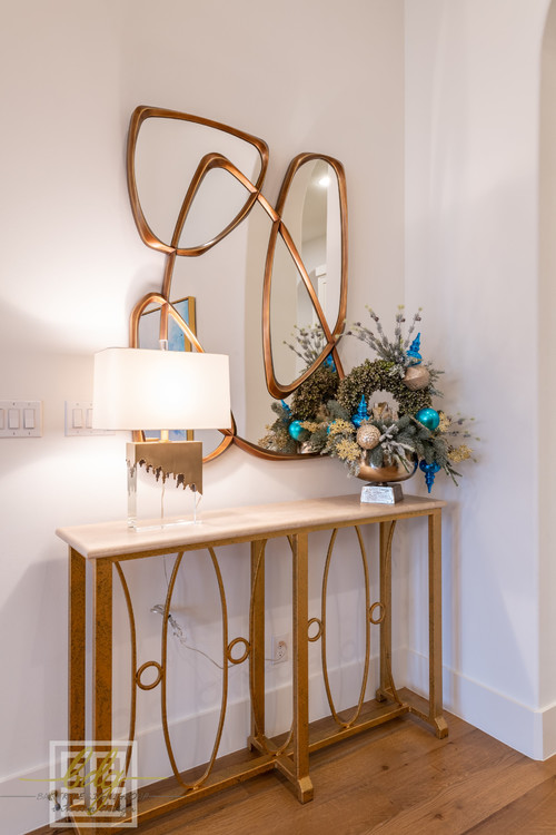 Sleek gold console decorated with a lamp and holiday arrangement of ornaments and greenery for a chic Christmas look.