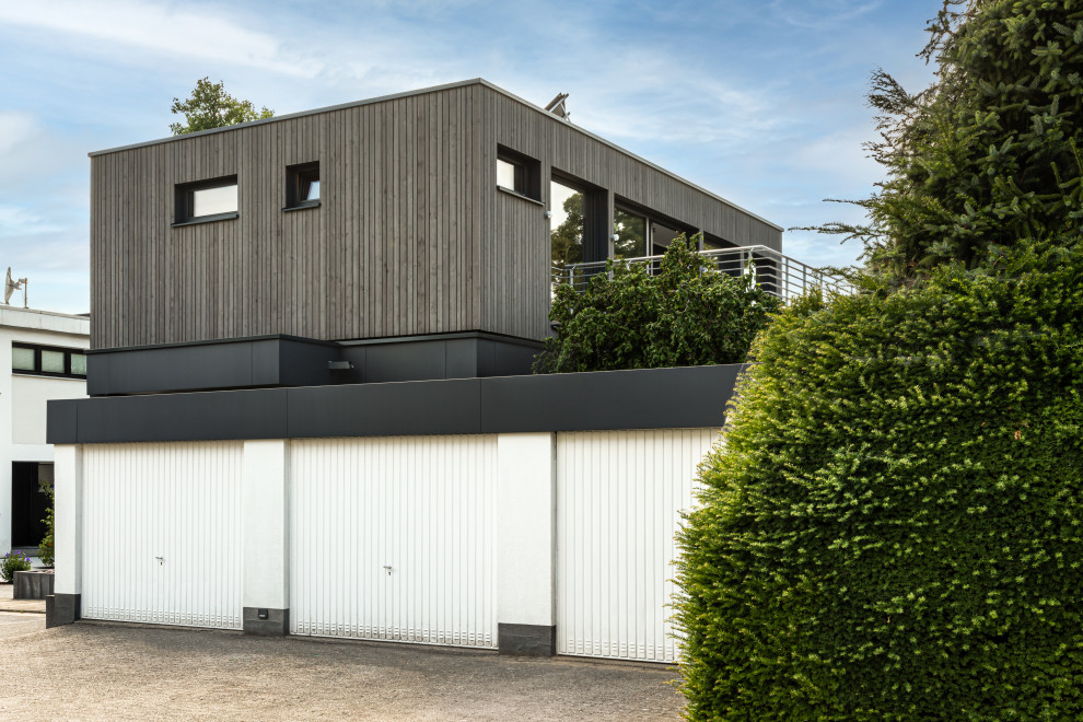 Aménagement d'une façade de maison moderne en bois et bardage à clin de taille moyenne avec un toit plat.