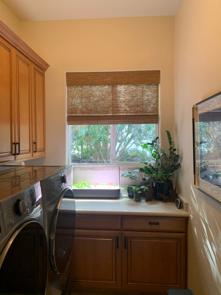 This is an example of a large transitional l-shaped dedicated laundry room in Salt Lake City with raised-panel cabinets, light wood cabinets, beige splashback, beige walls, travertine floors, a side-by-side washer and dryer, beige floor and beige benchtop.