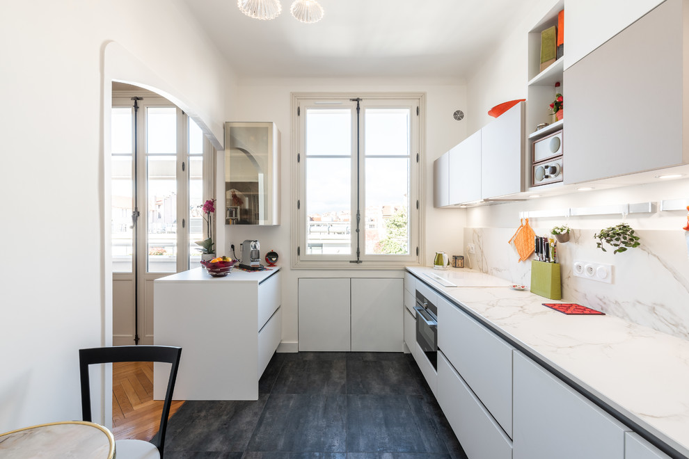 This is an example of a mid-sized contemporary galley separate kitchen in Lyon with an undermount sink, white cabinets, quartz benchtops, stainless steel appliances, ceramic floors, black floor, flat-panel cabinets, white splashback, stone slab splashback, a peninsula and white benchtop.