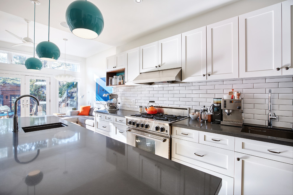 Example of a mid-sized transitional galley light wood floor enclosed kitchen design in Toronto with a single-bowl sink, shaker cabinets, white cabinets, quartz countertops, white backsplash, porcelain backsplash, stainless steel appliances and an island