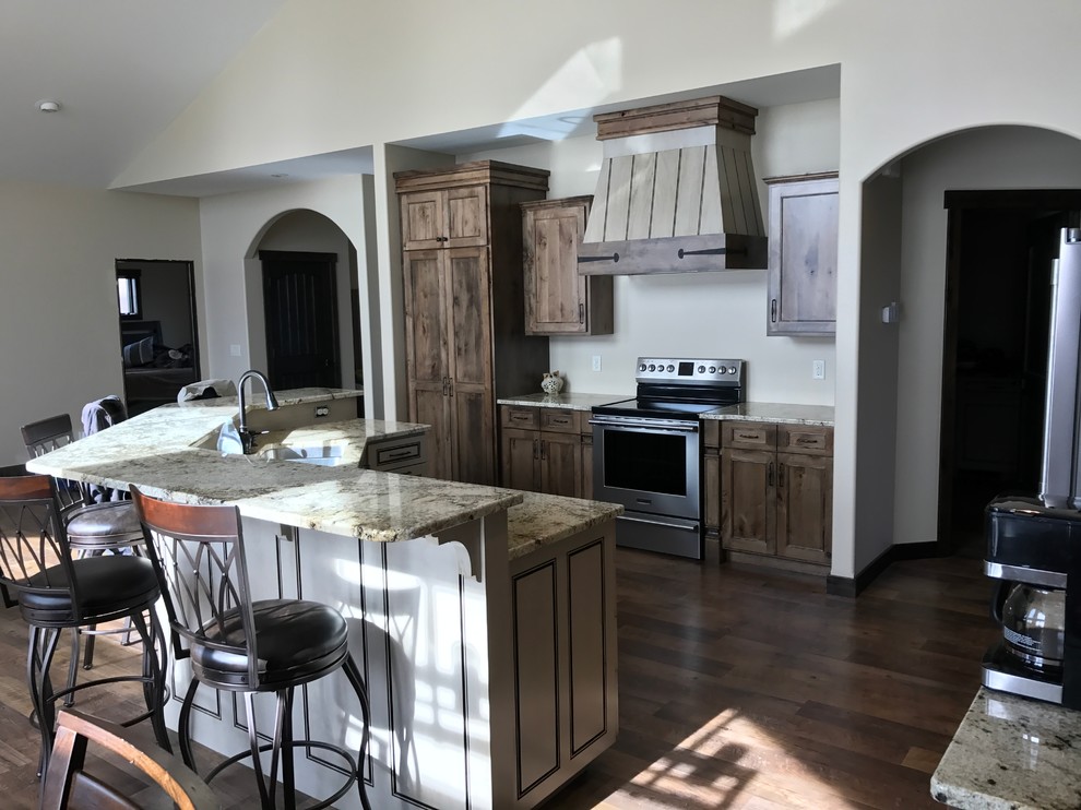 Open concept kitchen - large traditional dark wood floor and brown floor open concept kitchen idea with flat-panel cabinets, distressed cabinets, granite countertops, a double-bowl sink, stainless steel appliances and an island
