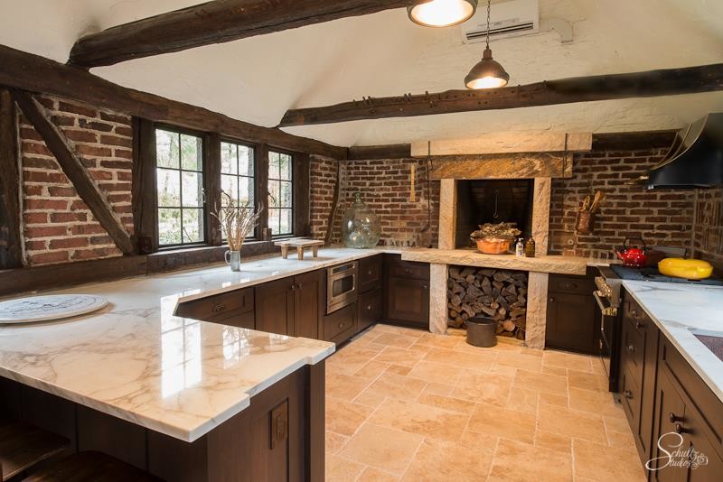 Large mountain style u-shaped travertine floor eat-in kitchen photo with an undermount sink, shaker cabinets, dark wood cabinets, marble countertops, red backsplash, stainless steel appliances and a peninsula