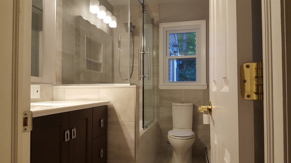 This is an example of a mid-sized modern master bathroom in New York with brown cabinets, a freestanding tub, a two-piece toilet, beige tile, porcelain tile, beige walls, porcelain floors, a console sink, marble benchtops and a sliding shower screen.