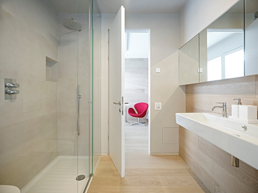 Photo of a contemporary bathroom in Other with light hardwood floors, a curbless shower, beige walls and a trough sink.