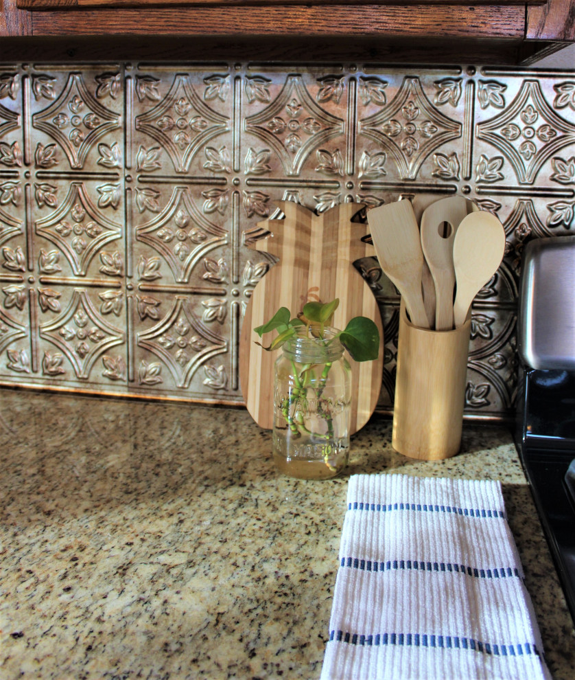 Example of a transitional single-wall kitchen design with medium tone wood cabinets, granite countertops, metallic backsplash, metal backsplash, stainless steel appliances and beige countertops