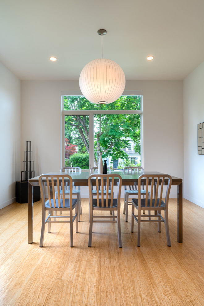 This is an example of a mid-sized open plan dining in Seattle with white walls, bamboo floors and brown floor.