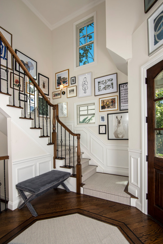 Photo of a transitional foyer in New York with white walls, dark hardwood floors, a single front door, a dark wood front door, brown floor and decorative wall panelling.