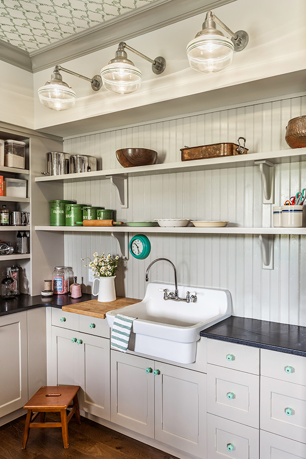 This is an example of a large country l-shaped utility room in Other with a farmhouse sink, shaker cabinets, grey cabinets, granite benchtops, grey walls, medium hardwood floors, a side-by-side washer and dryer and brown floor.